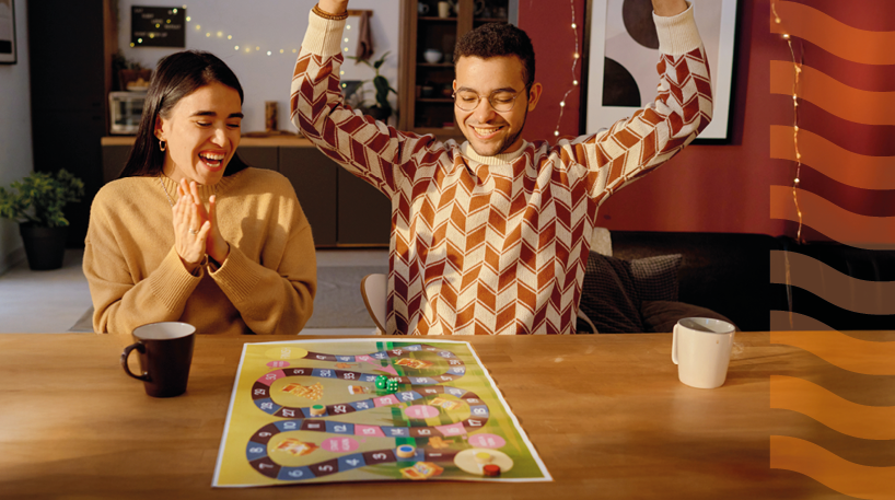 A young man celebrates his win in a board game against his friend. 
