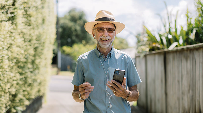 A smiling man using library services on his mobile phone.